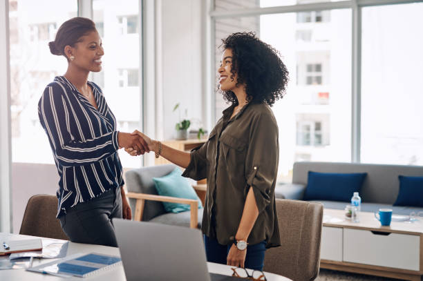 Cropped shot of two attractive young businesswomen in plant2wellness shaking hands while working together in a modern office